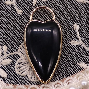 Macro shot of an elongated black heart-shaped stone pendant with gold metal edges