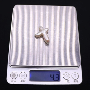 Vue macro d'une perle baroque naturelle en forme de croix de 4,3g sur une balance digitale