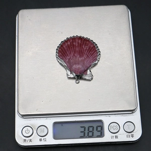 Vue détaillée d'un pendentif en coquillage naturel violet avec bord argenté sur balance