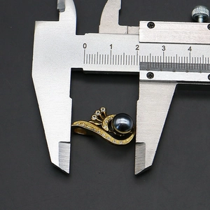 Detailed macro view showing the width of peacock wing pearl pendant using a caliper tool