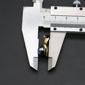 Detail view of a 10mm dark pearl pendant measured with a caliper on black background