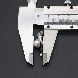 Macrodetail van een 8,5 mm parelhanger die nauwkeurig wordt gemeten met een schuifmaat