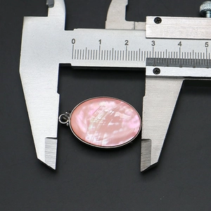 Vista macro del colgante ovalado de nácar rosa con una anchura de 2,7 cm en el calibrador