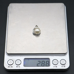 Dettaglio del ciondolo di perla da 2,88 g con zirconi su una bilancia digitale