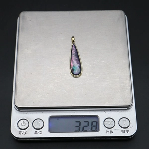 Detalle de un colgante de gota de nácar pesando 3,28g en una báscula de joyería