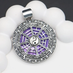 Macro shot of silver Tai Chi Bagua pendant with purple shell inlay and scroll texture