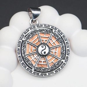 Macro detail of silver Tai Chi Bagua pendant with peach wood inlay and cloud patterns
