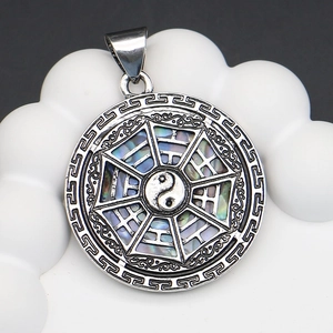 Macro shot of Yin Yang Tai Chi shell pendant with retro Bagua copper frame details