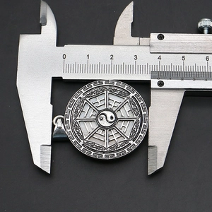 Detailed view showing a 40mm Tai Chi shell pendant measured with a caliper