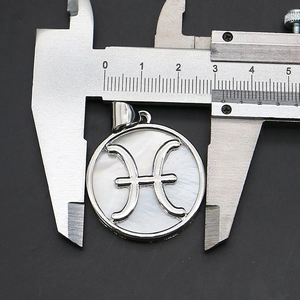 Detail view of Pisces zodiac shell pendant with silver frame showing 28mm size on caliper