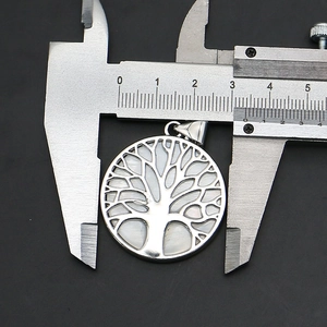 Macro view of a 30mm round Tree of Life pendant with shell inlay and silver metal plating
