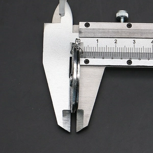 Detailed view of measuring the 2.5mm thickness of a round Tai Chi shell pendant