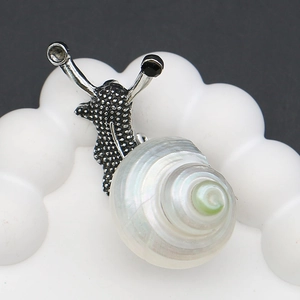 Macro detail of snail brooch with white shell spiral and sparkling gemstone eyes