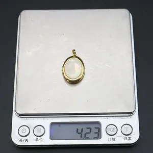 Close-up of golden oval locket pendant with iridescent shell inlay on weighing scale