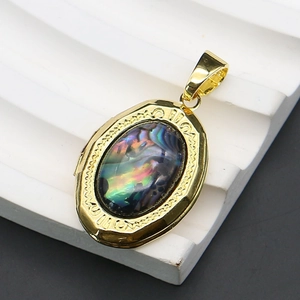 Detailed macro view of an oval abalone shell locket with vintage gold-plated engravings