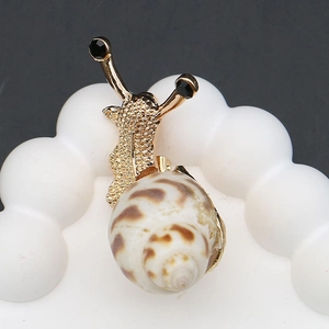 Detailed view of snail brooch with gold alloy body and natural spiral shell texture