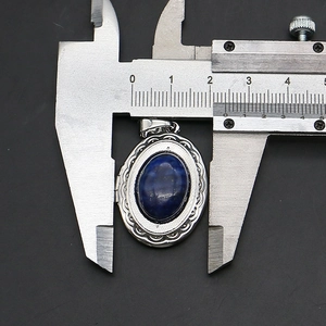 Detailed view of an oval blue stone locket measured with calipers showing 25mm width