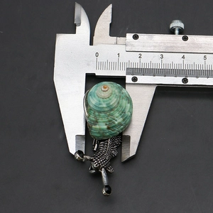 Macro shot of snail shell brooch with caliper measuring precise 4cm length and texture