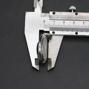Caliper measuring the 8.5mm thickness of an oval locket pendant with blue stone and engraving