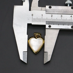 Macro detail of heart locket pendant being measured with caliper showing 15mm width