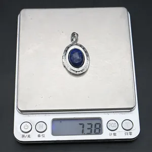 Lapis lazuli oval locket pendant being weighed on a digital scale showing 7.38 grams