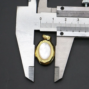 Détail macro du pendentif ovale en or avec nacre blanche et motif de vagues gravé