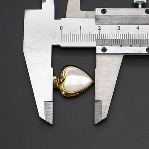 Macro shot of heart-shaped pearl pendant showing 20mm dimensions with metal calipers