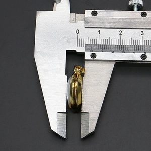 Detail showing measurement of the abalone shell heart locket thickness using a caliper