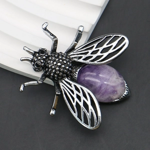 Makro-Detail der Bienenbrosche mit verzierten Flügeln und violettem Edelstein