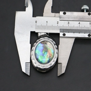 Makroaufnahme vom ovalen Abalone-Muschel-Medaillon (23mm) mit floralen Gravuren