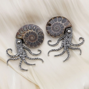 Vintage octopus brooches with spiral ammonite shells on a soft silk fabric background