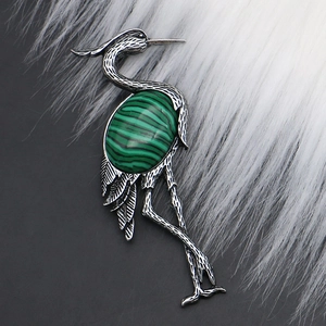 Macro detail of crane-shaped brooch with vintage silver finish and green striped stone inlay