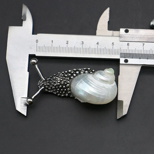 Macro view of a snail shell brooch with natural shell inlay measured by calipers