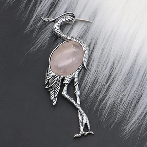 Macro shot of silver crane brooch featuring a large oval rose quartz on black and white fur