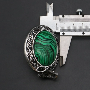 Detailed macro shot of vintage oval malachite pendant measuring 30mm with a caliper