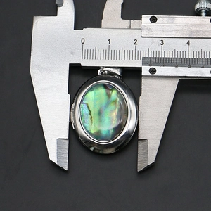 Messung des ovalen Abalone-Muschel-Medaillons zeigt 25 mm Breite mit digitalem Messschieber