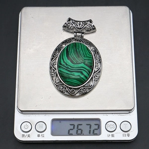 Macro detail of oval malachite pendant with vintage silver hollow design on a digital scale