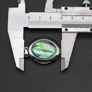Makroansicht der Breitenmessung eines ovalen Abalone-Muschel-Medaillons mit Messschieber