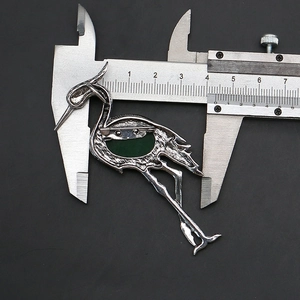 Detail view of bird brooch back showing silver alloy plating and safety pin mechanism