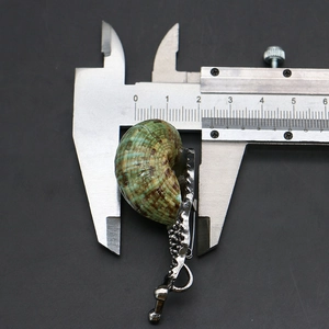 Macro shot of a shell pendant showing a width of 23mm with a digital caliper measurement
