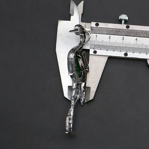 Detail view of bird crane brooch with dark green oval stone inlay and silver texture