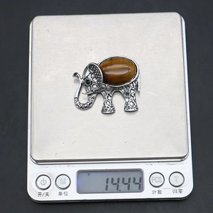 Macro view of a 14.44g elephant brooch pendant featuring an oval tiger eye gemstone