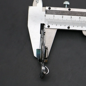 Macro side view of vintage metal crane brooch showing thickness with calipers