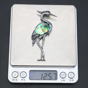Macro detail of crane brooch made of silver alloy and iridescent abalone shell inlay
