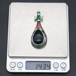 Vue macro d'une broche luth de style ethnique pesée sur une balance de bijoux