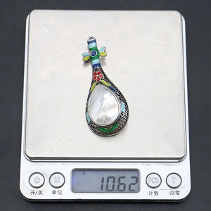 Détail d'une broche vintage en turquoise et nacre sur une balance de précision numérique