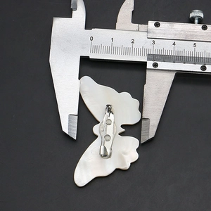 Macro detail of natural butterfly shell brooch back showing metal pin and size measurement