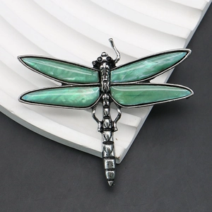 Macro detail of vintage dragonfly brooch with green wings and textured metallic body