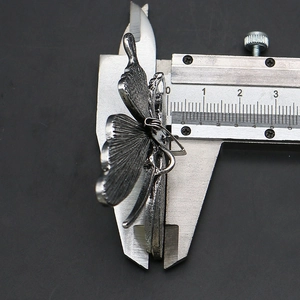 Macro shot showing dimensions of silver butterfly pendant using a metal caliper tool