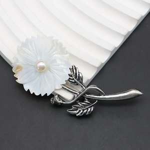 Macro shot of flower brooch featuring white shell petals and a central pearl detail